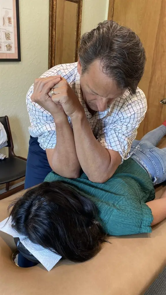 Dr. Dean Hegarty performing a chiropractic adjustment on a patient’s mid back